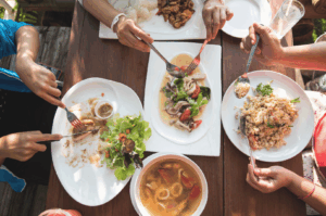 Group of friends sharing a variety of dishes at a round table, capturing the warmth and togetherness of communal dining in Asia.
