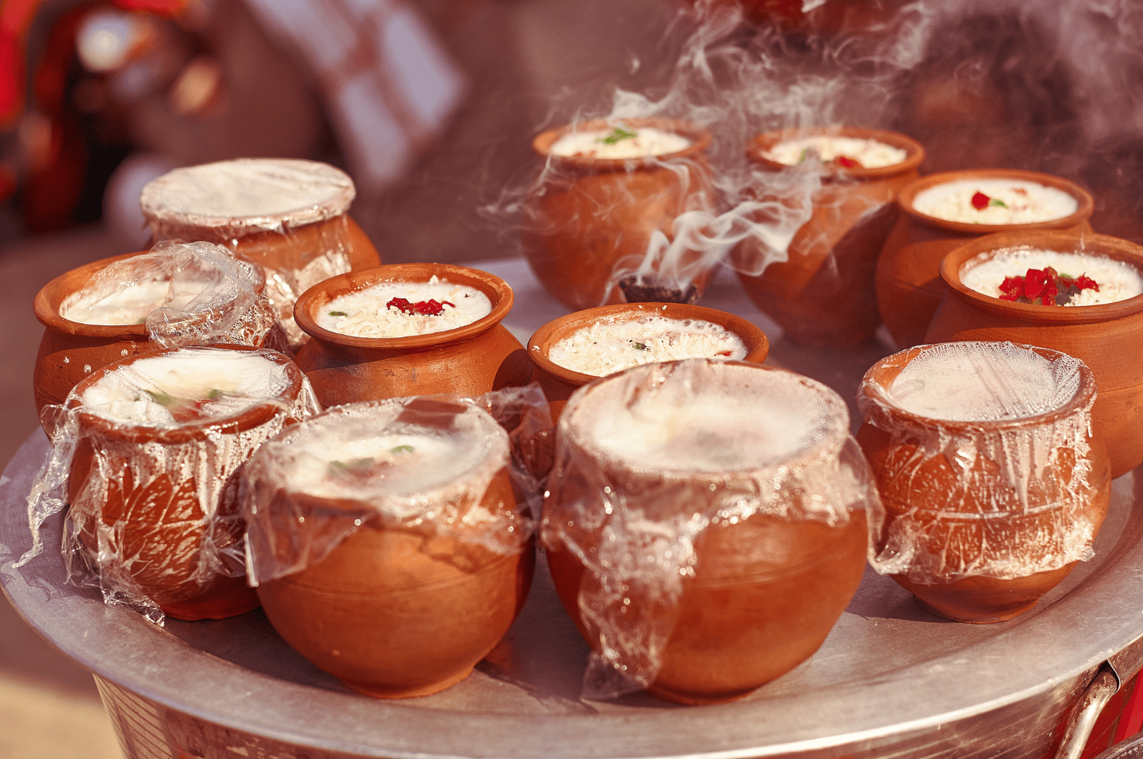 Indian-Lassi- (4) Cluster of traditional clay pots filled with frothy lassi or mishti doi, some topped with nuts and dried fruits, others steaming gently—capturing India’s festive yogurt rituals and the earthy allure of earthenware presentation.