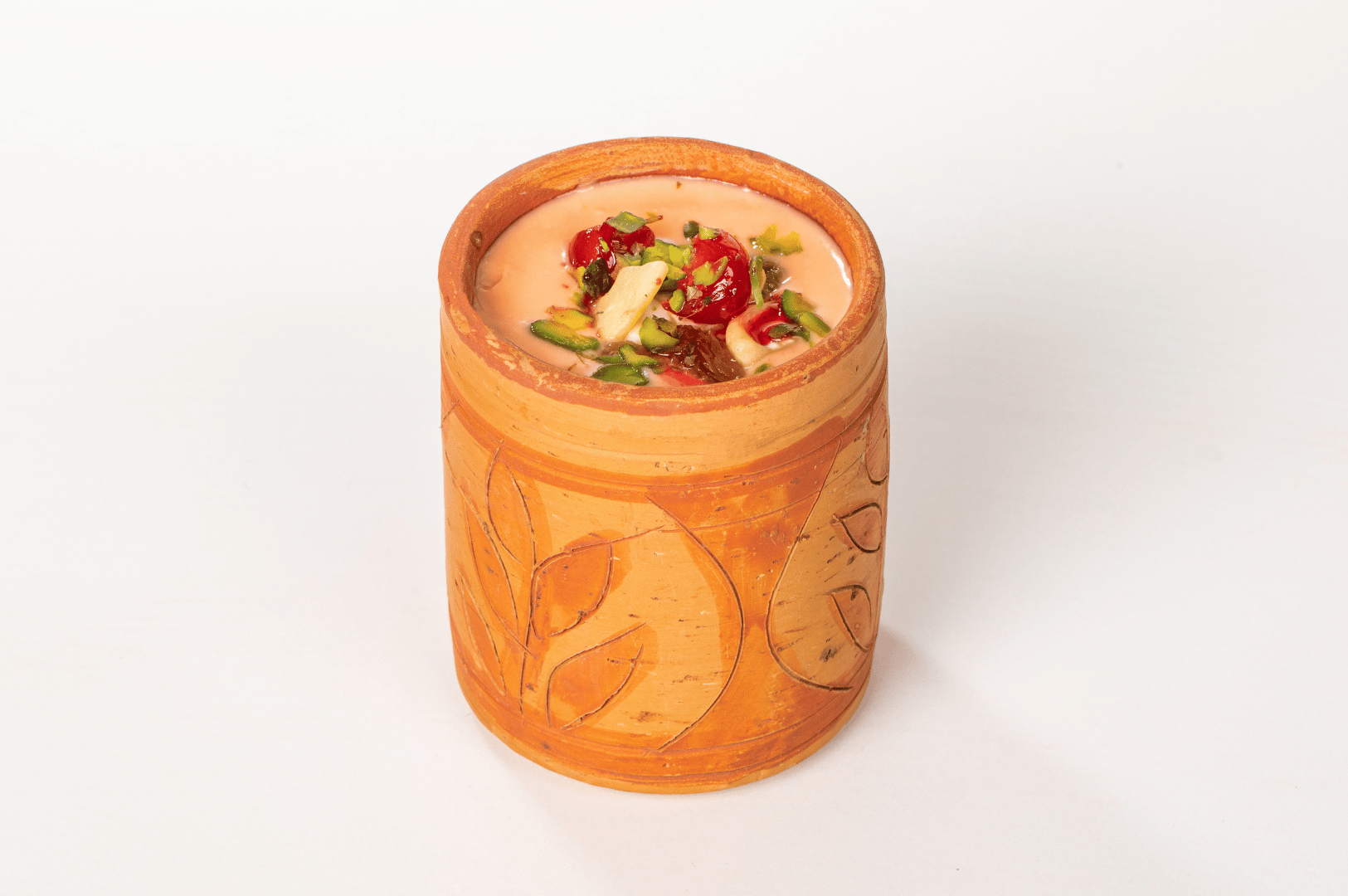 Indian-Lassi- (5) Decorative clay cup filled with creamy kulfi or rabri, topped with pistachios, almonds, and red fruit—showcasing India’s indulgent yogurt-based desserts and the artisanal charm of traditional serveware.