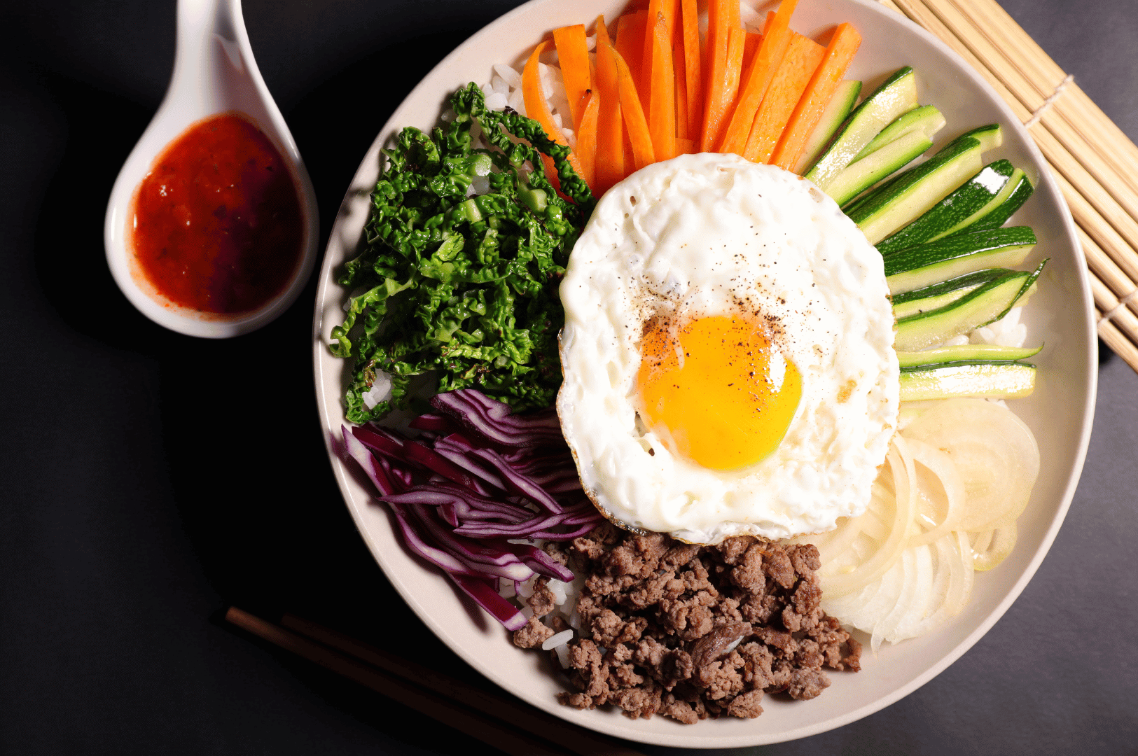 Jeonju- (2) Overhead shot of a vibrant Jeonju-style bibimbap in a ceramic bowl, topped with sliced beef, sautéed vegetables, kimchi, and a sunny-side egg, showcasing Korea’s culinary capital’s signature balance of color and texture.