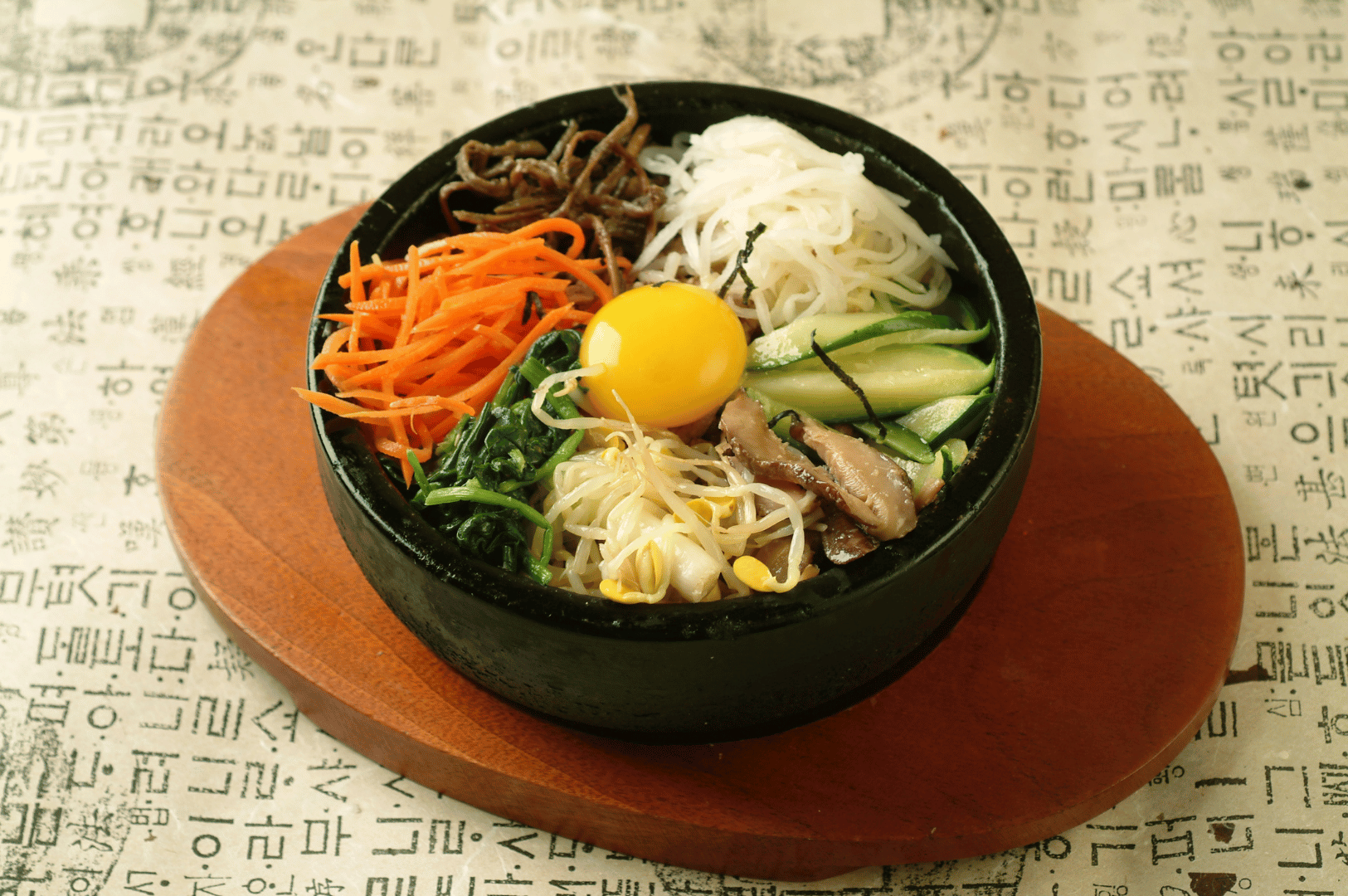 Jeonju- (5) A rustic bowl of Jeonju-style bibimbap on a wooden table, topped with colorful vegetables, egg, and beef, illustrating Korea’s culinary capital for an article on why Jeonju makes it best.