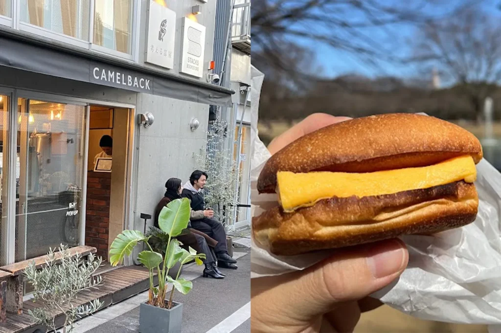 A person holding a Japanese tamagoyaki (omelet) sandwich from Camelback Sandwich & Espresso in Tokyo, with the shop exterior shown on the left.