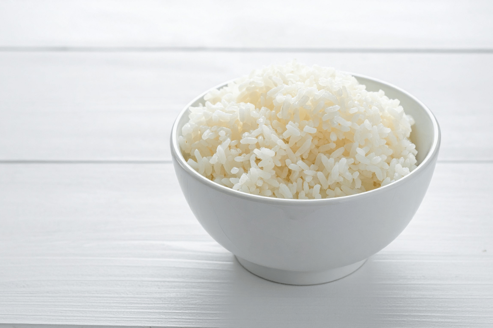 Fluffy white rice served in a ceramic bowl—an essential base for Singapore’s beloved Hainanese chicken rice, featured in The Ultimate Hainanese Chicken Rice Recipe: A Deep Dive.