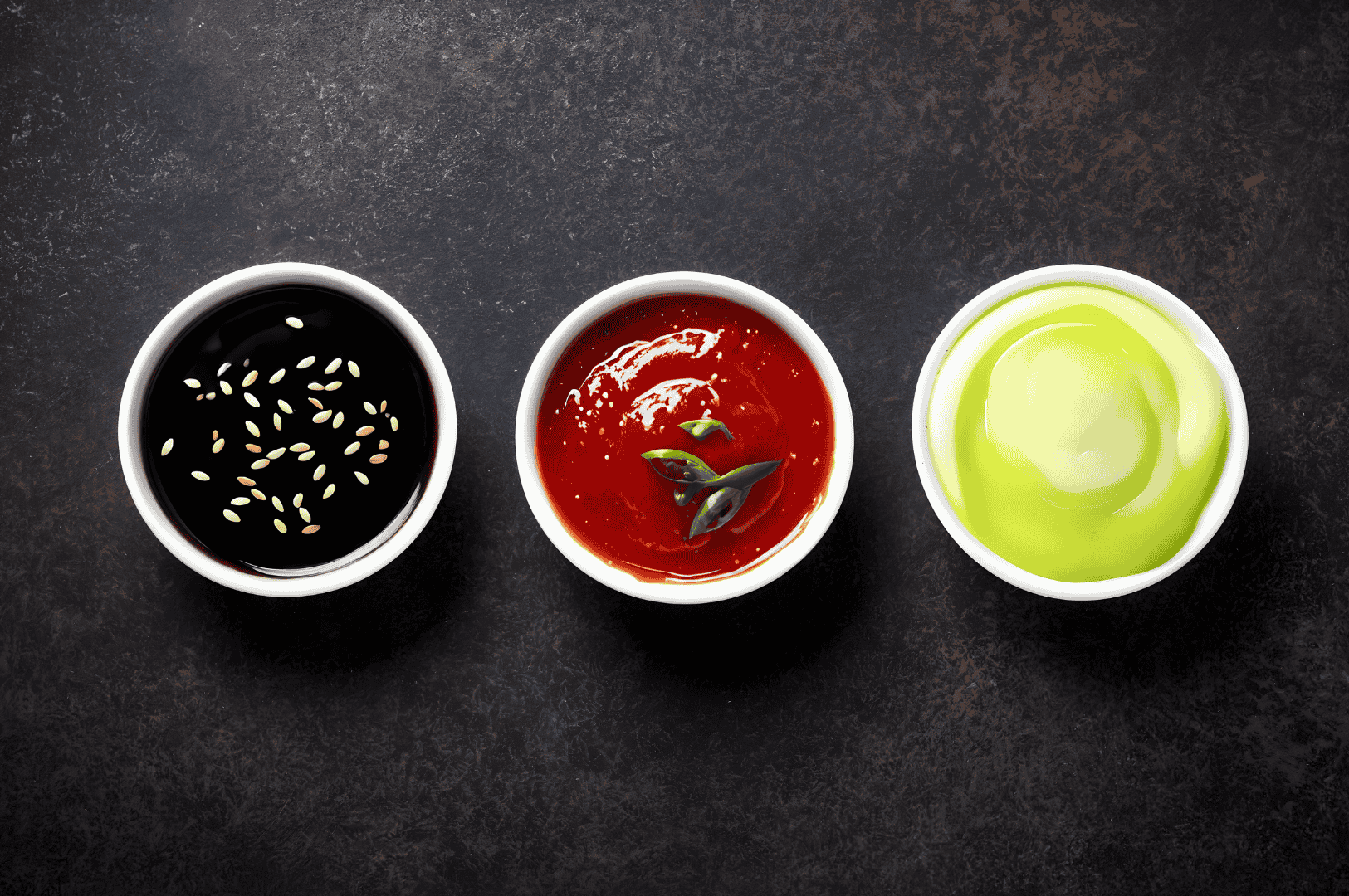 Trio of dipping sauces—dark soy with sesame, vibrant chili with herbs, and creamy green ginger—served for Singapore’s Hainanese chicken rice, featured in The Ultimate Hainanese Chicken Rice Recipe: A Deep Dive.