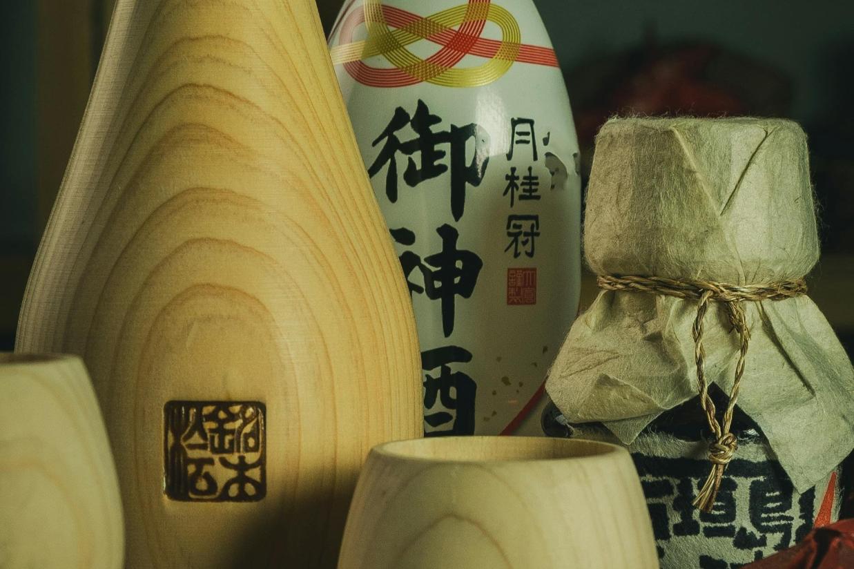 Rice WIne - 2 a close-up photo of a traditional Japanese sake accompanied by its wooden cups and bottles.