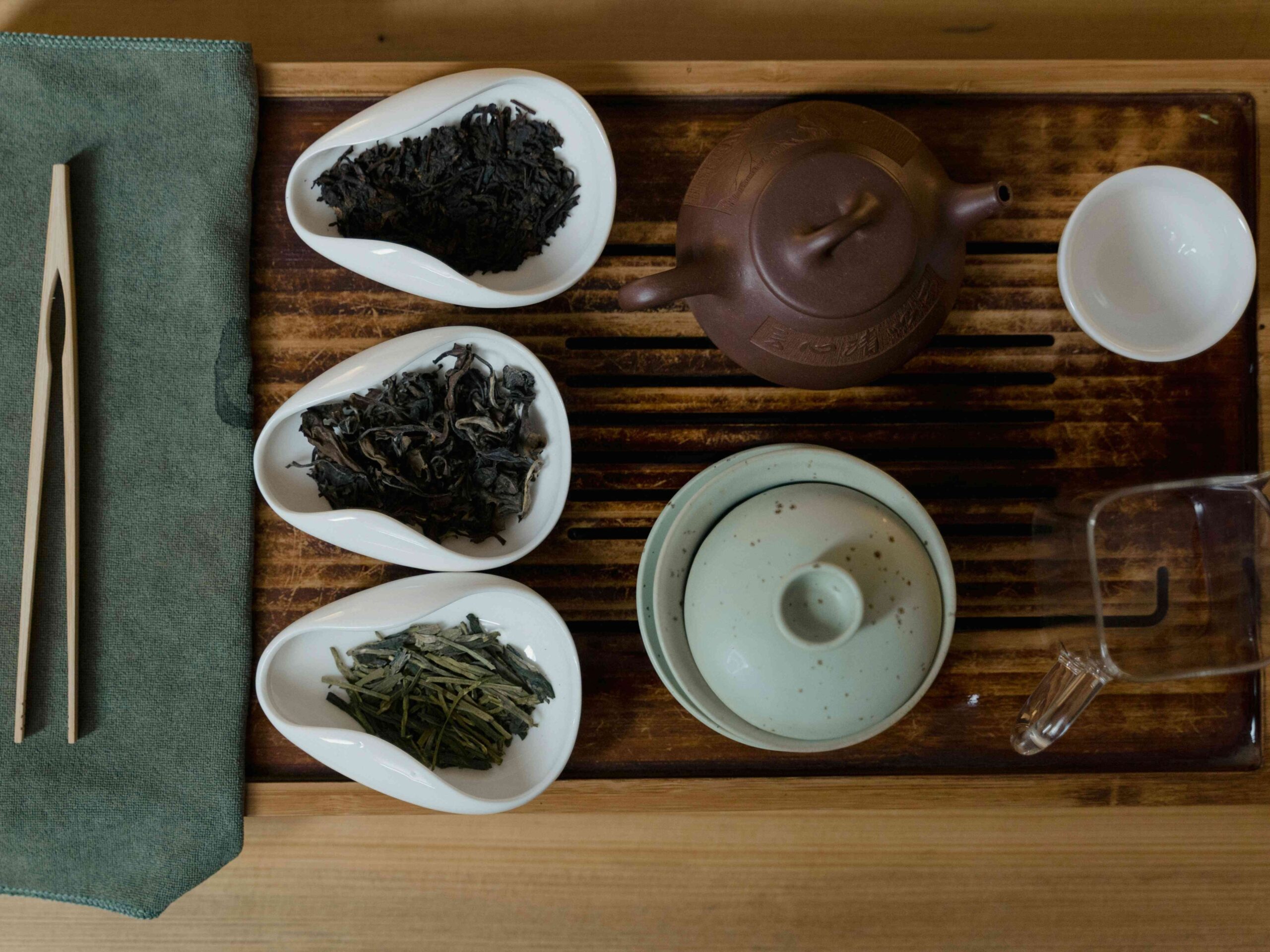 A tea set displayed with three different types of tea leaves.