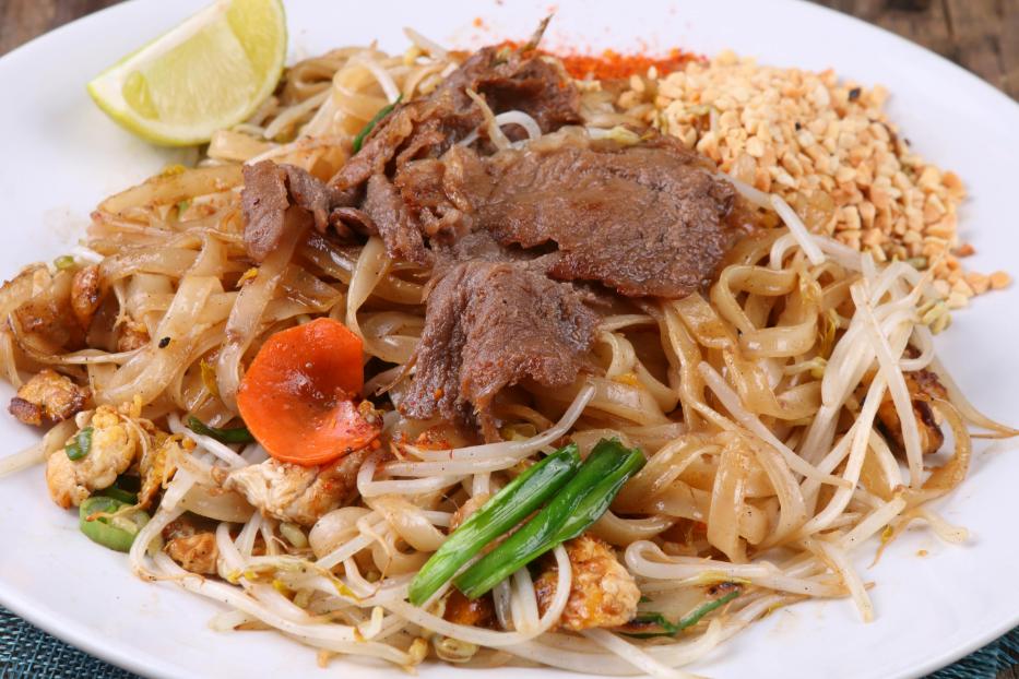 The image features a plate of Pad Thai, a Thai noodle dish, with ingredients like noodles, bean sprouts, green onions, carrots, tofu, and beef.