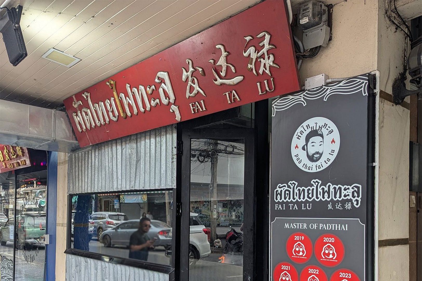 Exterior storefront of Pad Thai Fai Ta Lu in Bangkok, featuring the restaurant signage and Michelin Bib Gourmand awards from 2019 to 2023.