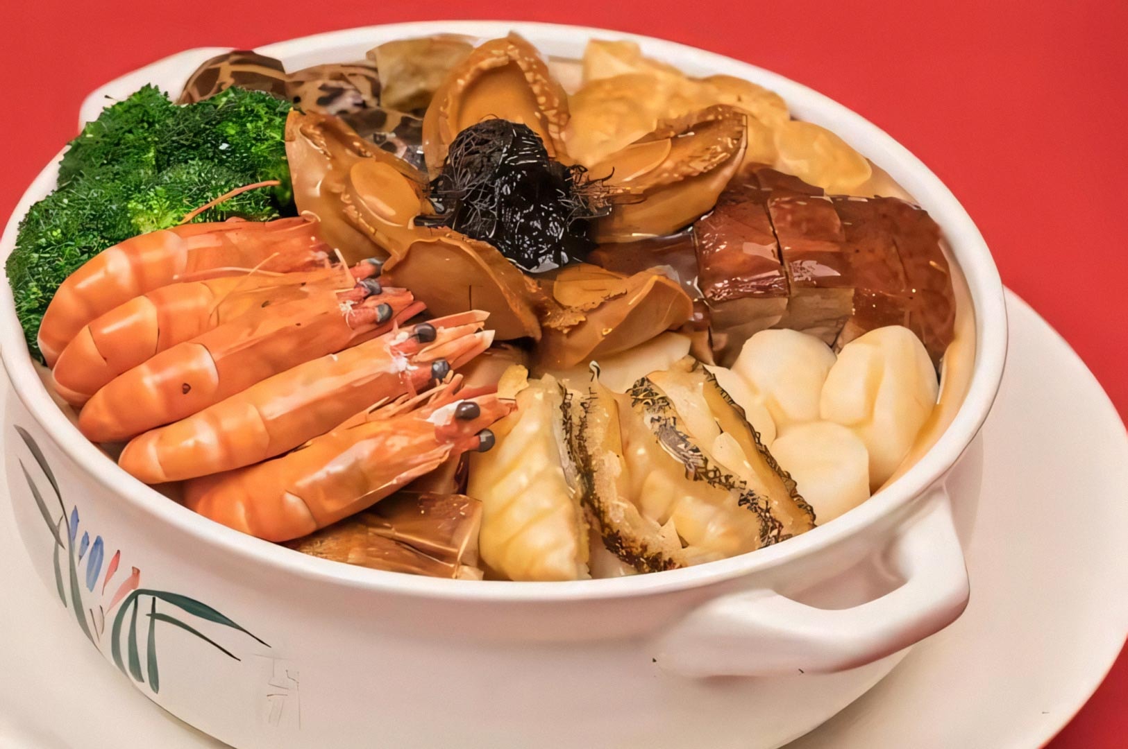 A traditional Chinese Poon Choi dish featuring layers of prawns, abalone, roast pork, scallops, and broccoli arranged in a white ceramic bowl.