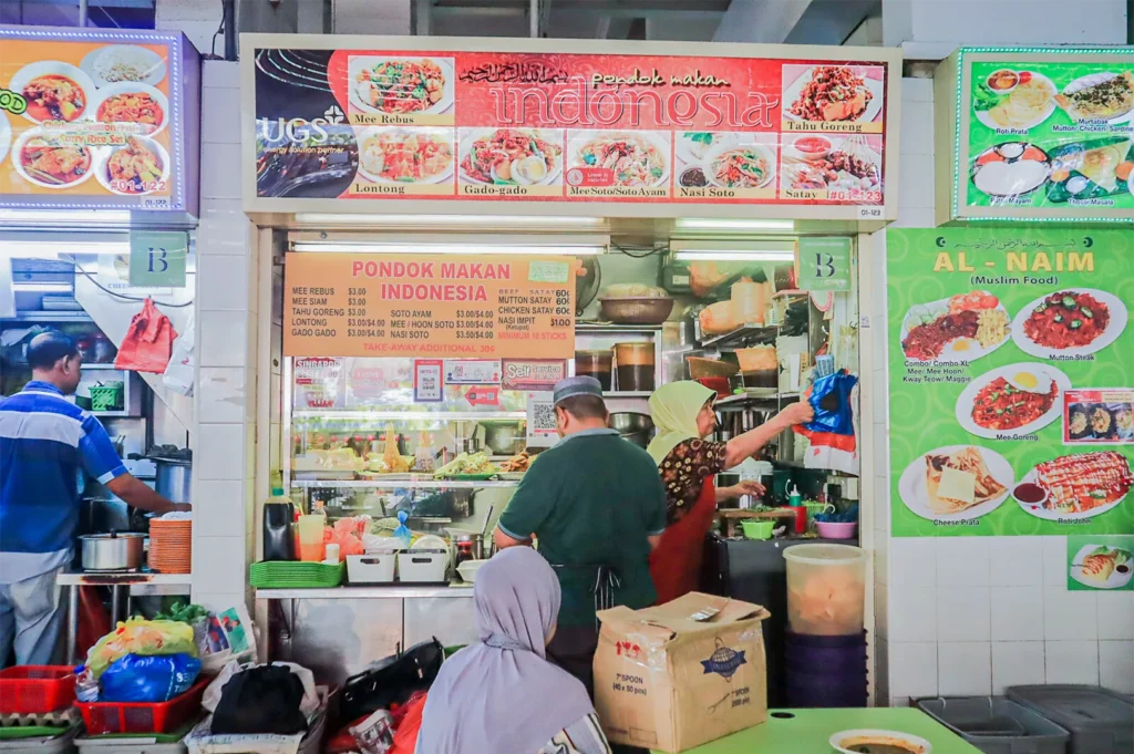 A vibrant Singaporean hawker stall named Pondok Makan Indonesia displaying a menu of Mee Rebus, Gado-Gado, and Satay.