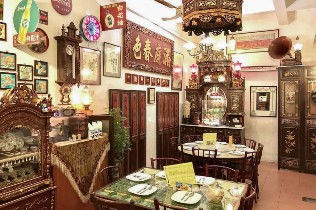 A richly decorated traditional Chinese restaurant interior featuring ornate wood carvings, vintage clocks, and antique decor.