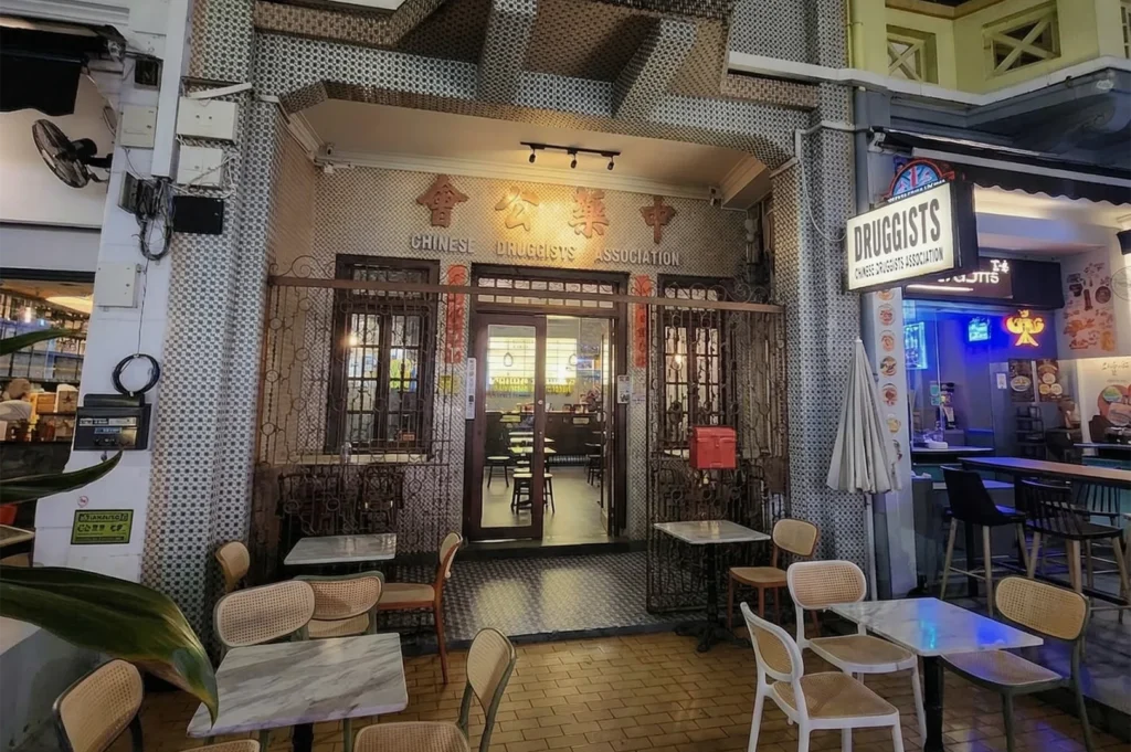 The unique facade of Druggists bar in Singapore, located in the historic Chinese Druggists Association building with intricate tile work.