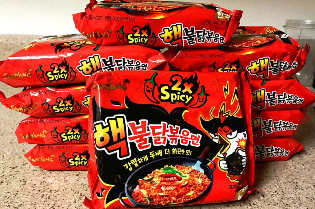 Multiple packs of Samyang 2x Spicy Buldak Korean instant noodles stacked together showcasing the famous extreme spicy ramen flavour