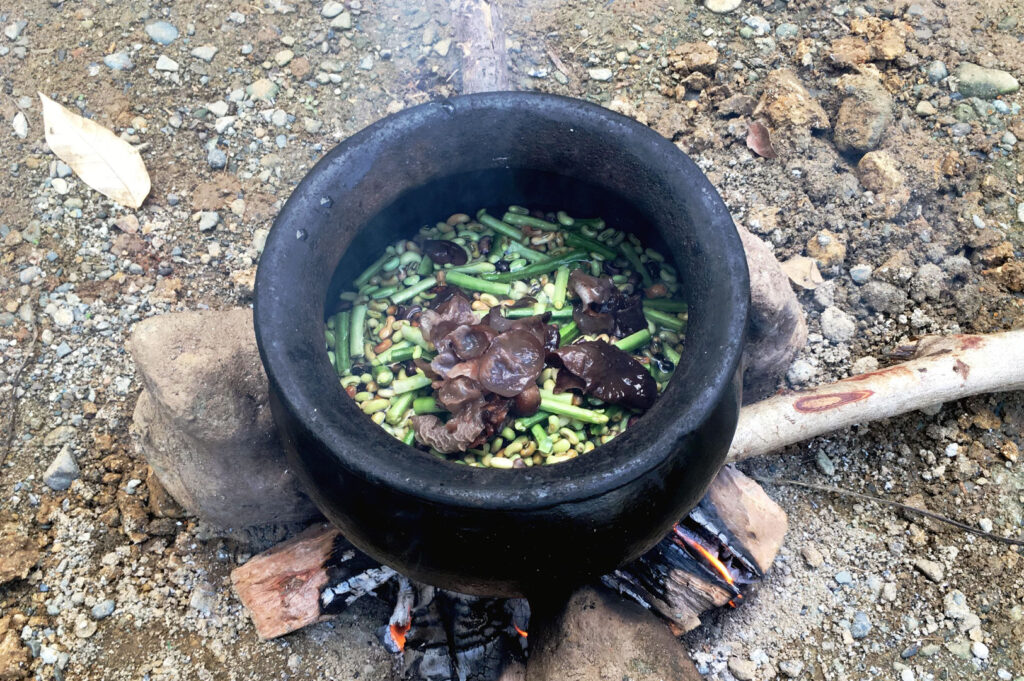 Traditional Cordillera mountain cooking pot over a wood fire with vegetables and broth being prepared outdoors in Benguet