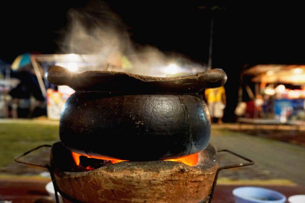 Traditional Hong Kong clay pot rice cooking over open charcoal flame with steaming black clay pot at a Temple Street night market