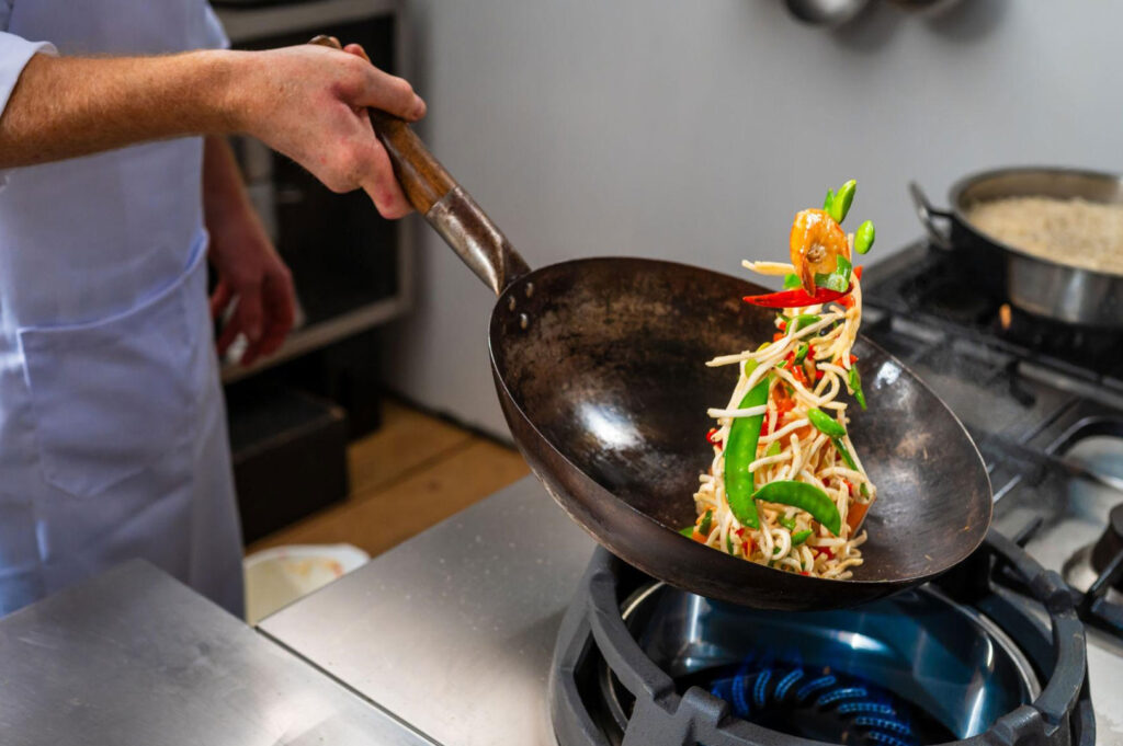Traditional wok cooking Chinese vegetables over high flame with garlic, ginger, scallions, and chillies