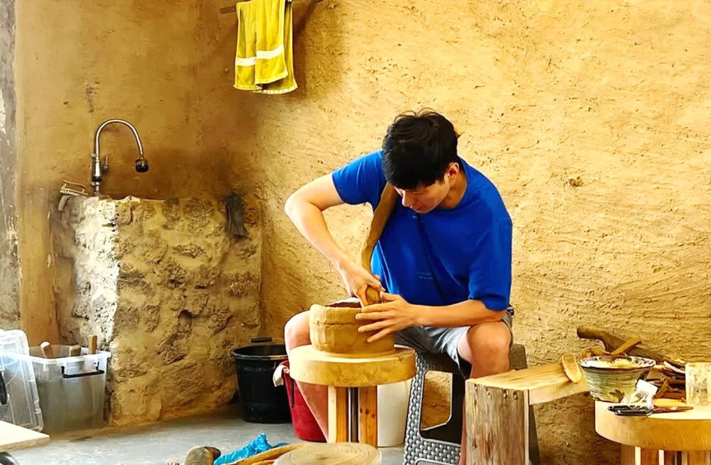 Traditional Korean artisan crafting wooden makgeolli bowls in a rustic workshop, preserving Korea's rice wine drinking heritage and traditional craftsmanship.