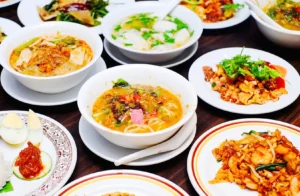 Spread of Malaysian dishes including laksa, noodles, and shared plates at The Malayan Council Singapore, showcasing authentic Malaysian food culture.