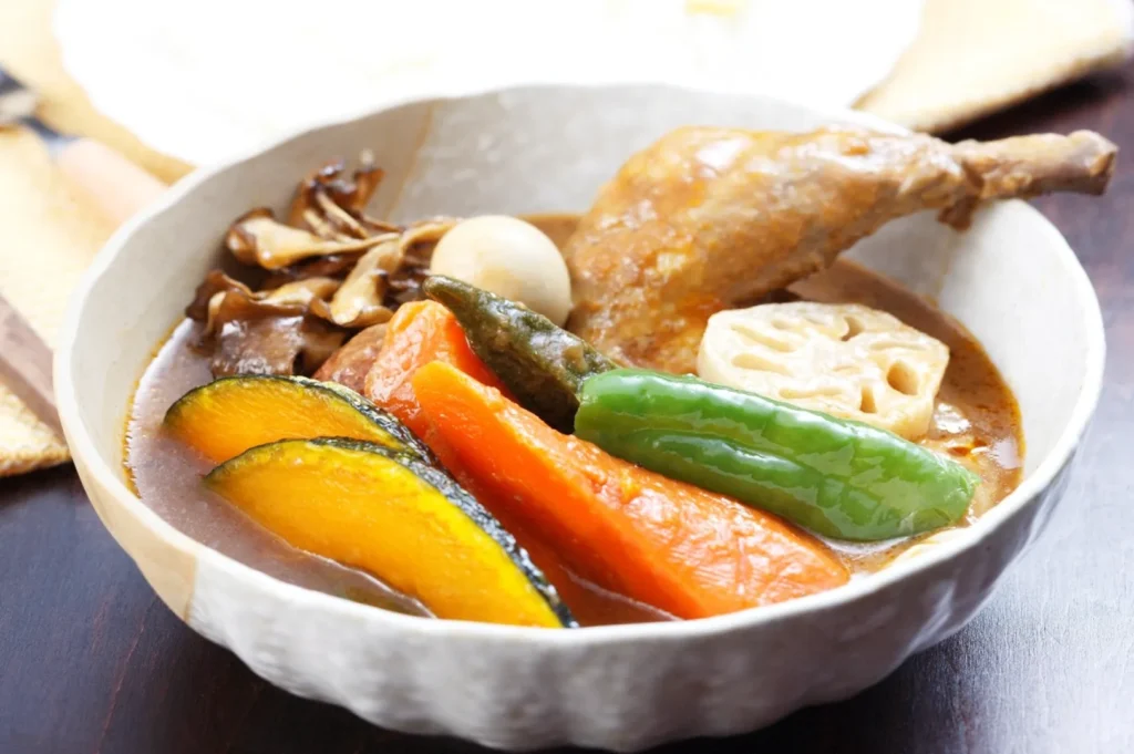 Japanese chicken curry with pumpkin, lotus root and vegetables served in a bowl on a wooden table