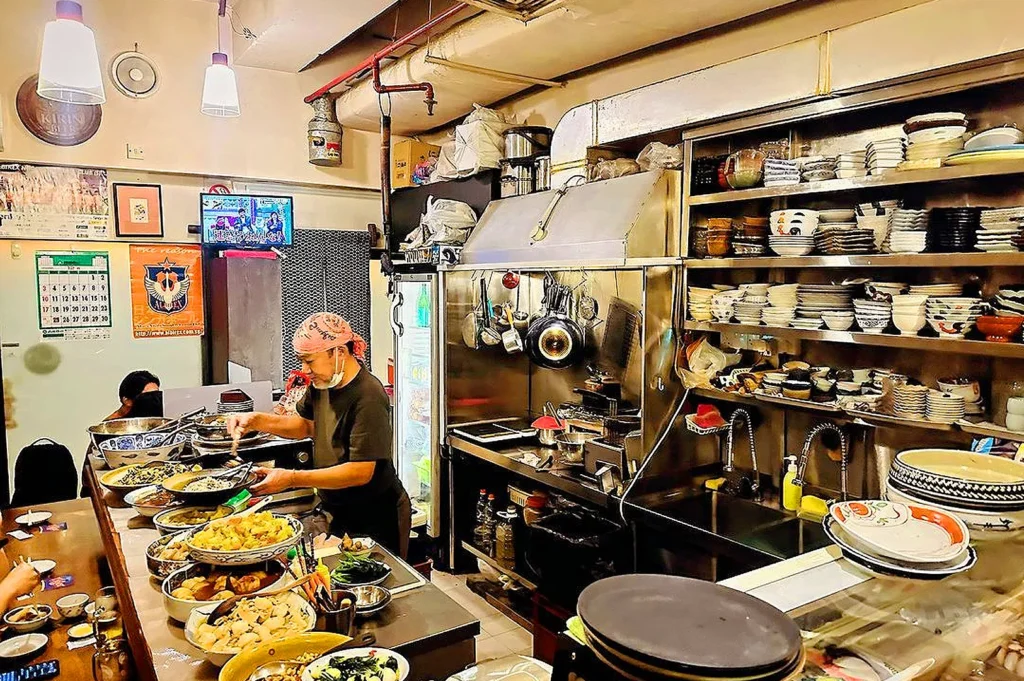 Open kitchen at Izakaya Naniwa Singapore where chefs prepare authentic Japanese dishes in a traditional izakaya setting.