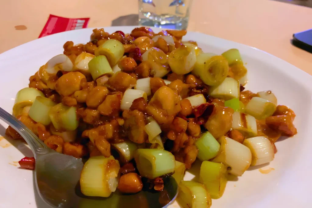 Classic Sichuan stir-fried chicken dish with peanuts, leeks, and chili peppers showcasing bold regional Chinese flavors.