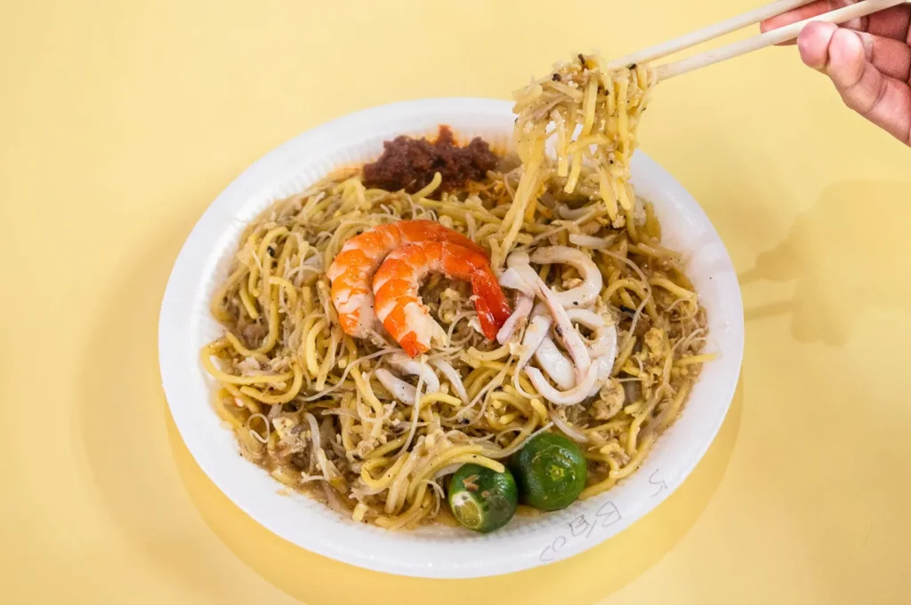 Plate of Singapore fried Hokkien mee with prawns, squid, sambal chilli and calamansi lime