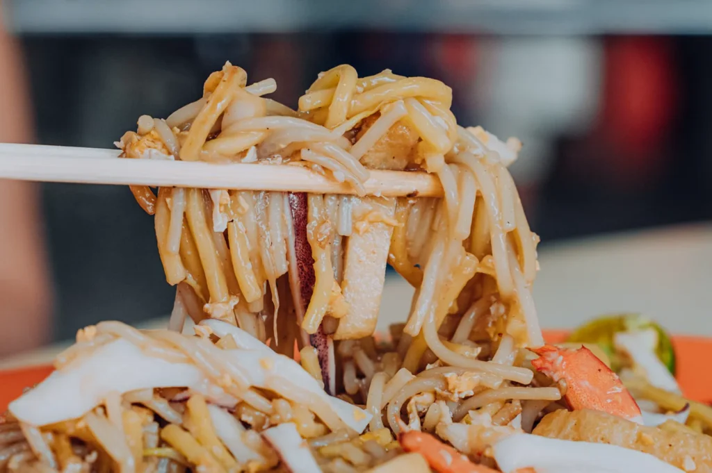 Hong Heng Fried Sotong Prawn Mee noodles lifted with chopsticks featuring squid, prawns and wok-fried seafood noodles