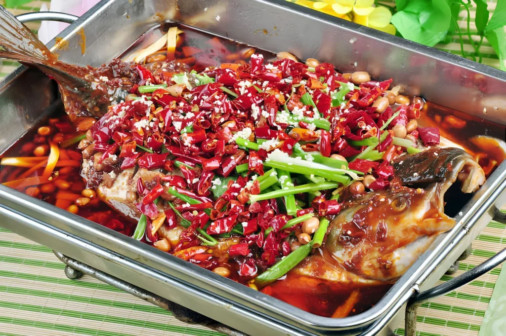 Signature Sichuan boiled fish topped with dried red chilies, peanuts, and aromatic spices for intense mala flavor.