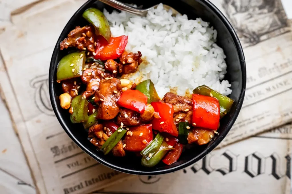 Homemade Kung Pao chicken rice bowl with bell peppers, peanuts, and spicy Sichuan sauce.
