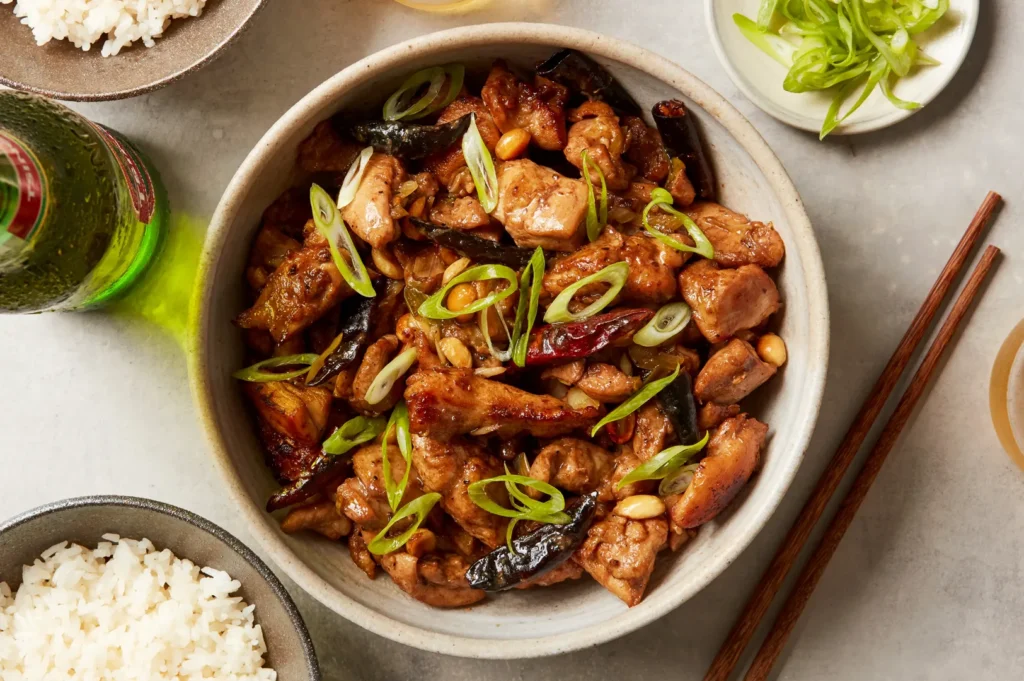 Homemade Kung Pao chicken featuring tender chicken pieces, roasted peanuts, dried red chilies, and scallions in a savory Sichuan-style sauce.