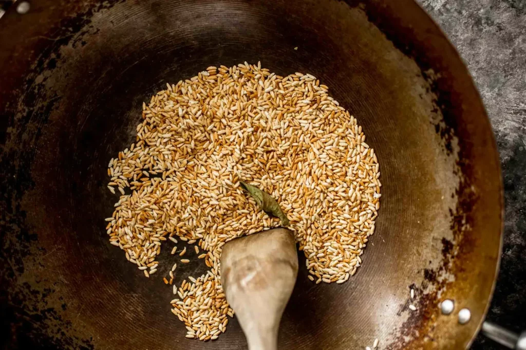 Traditional toasted rice powder being roasted in a wok for authentic Thai and Lao larb seasoning.