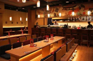 Traditional Japanese izakaya interior in Singapore with communal tables, sushi counter and warm ambient lighting