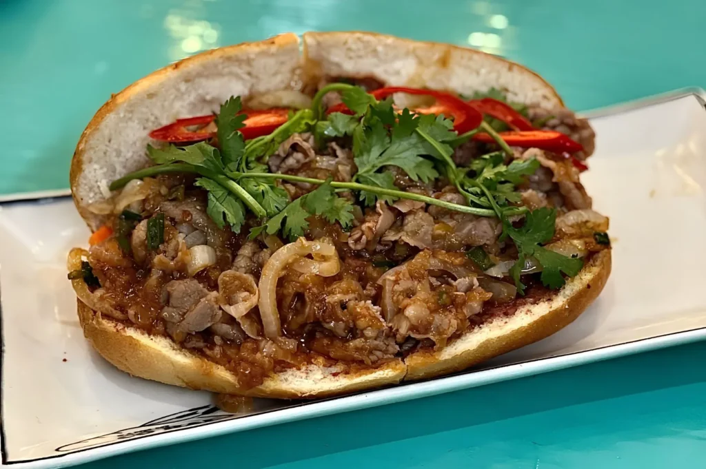 Vietnamese grilled beef bánh mì with fresh cilantro, pickled vegetables, and chili on a crispy baguette at Co Hai Banh Mi Singapore.