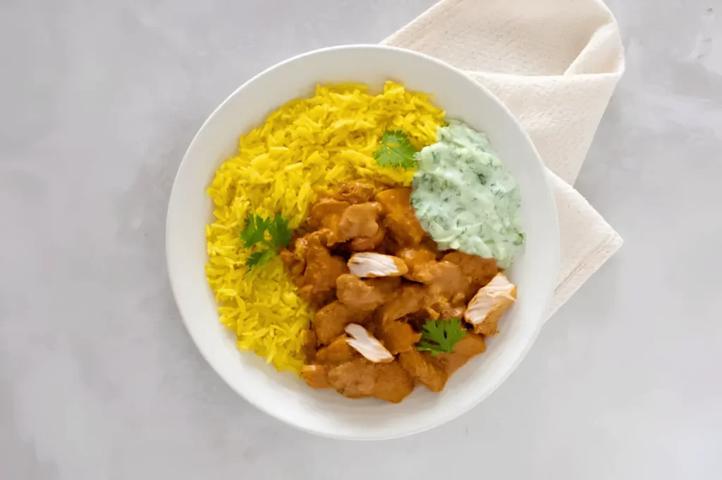 One-pan chicken curry with jeera rice and cucumber raita served in a bowl