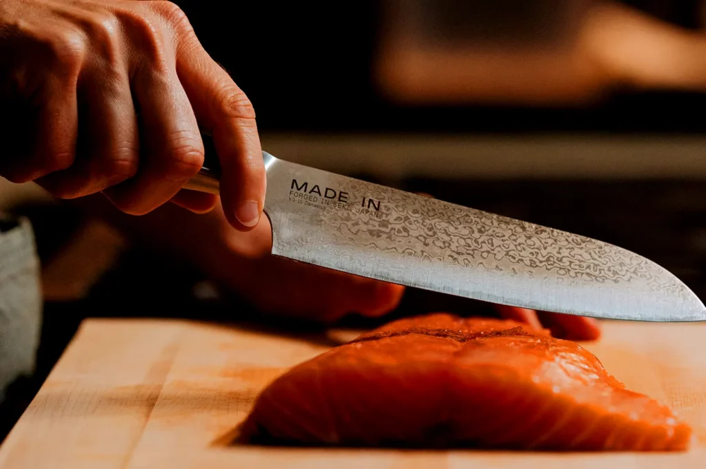 Japanese chef knife slicing fresh salmon at Hanashizuku Japanese restaurant, showcasing traditional Japanese knife skills