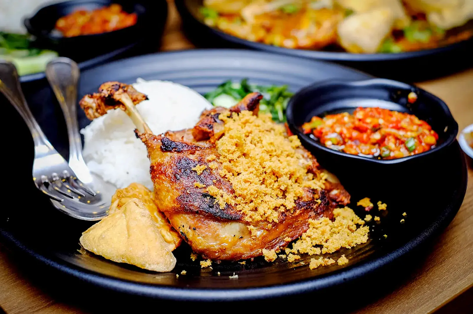 Crispy fried duck with white rice, savory crumbs, tofu, and spicy sambal at Bebek Goreng Pak Ndut
