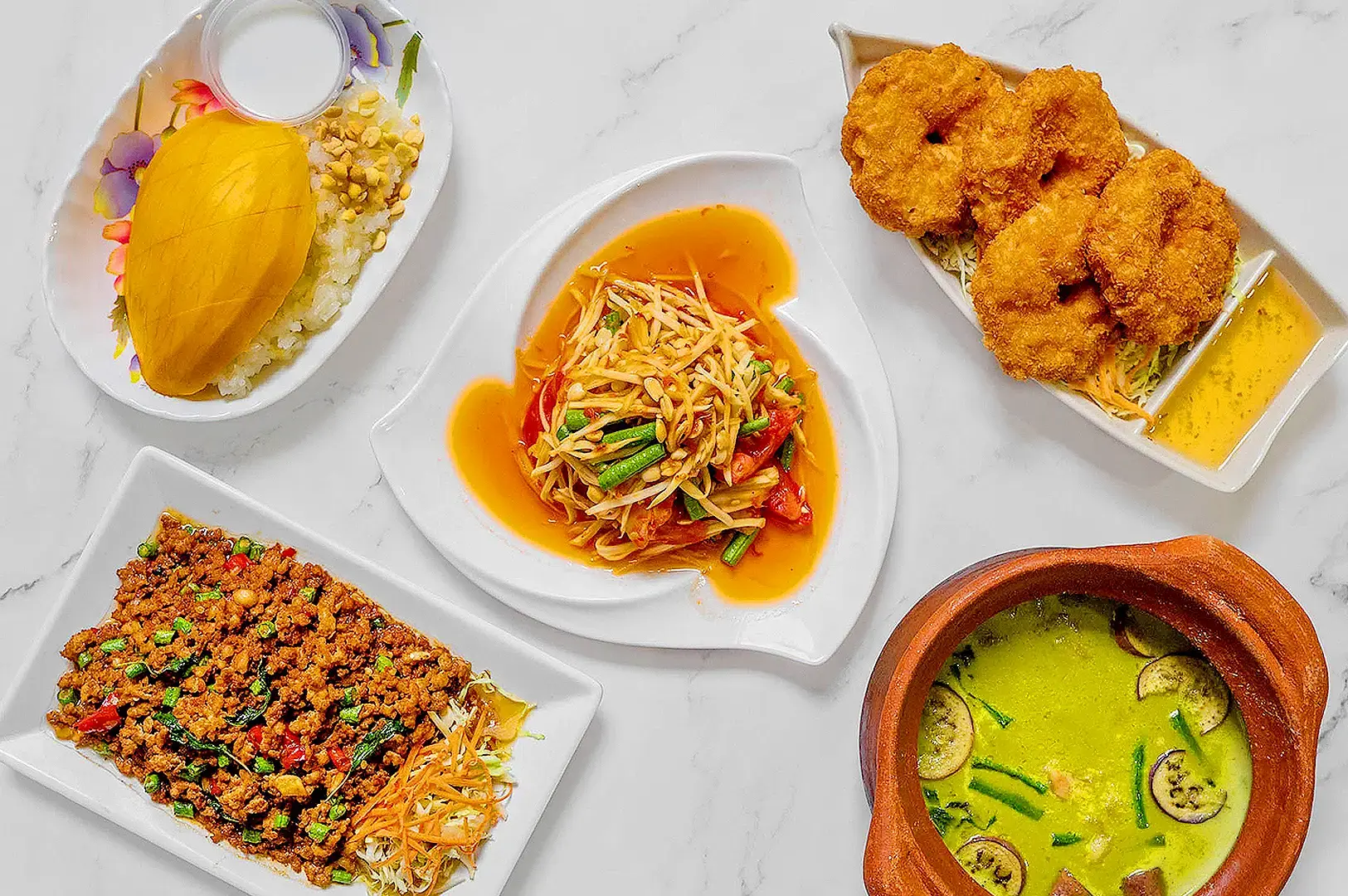 Assorted authentic Thai dishes including mango sticky rice, som tam, crispy prawns, minced meat salad and green curry