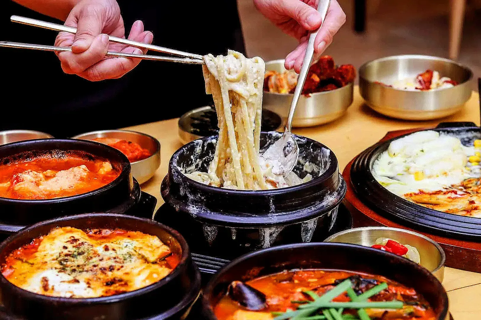 Korean noodle dish served with spicy stews, kimchi, and traditional banchan at SBCD Korean Tofu House