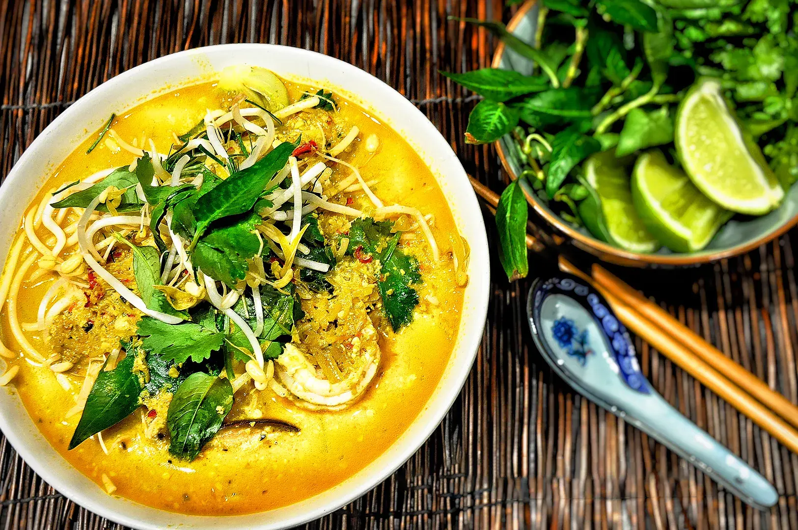 Creamy vegan laksa with coconut curry broth, rice noodles, bean sprouts, fresh laksa leaves, coriander, lime, and flavorful Asian vegetarian ingredients