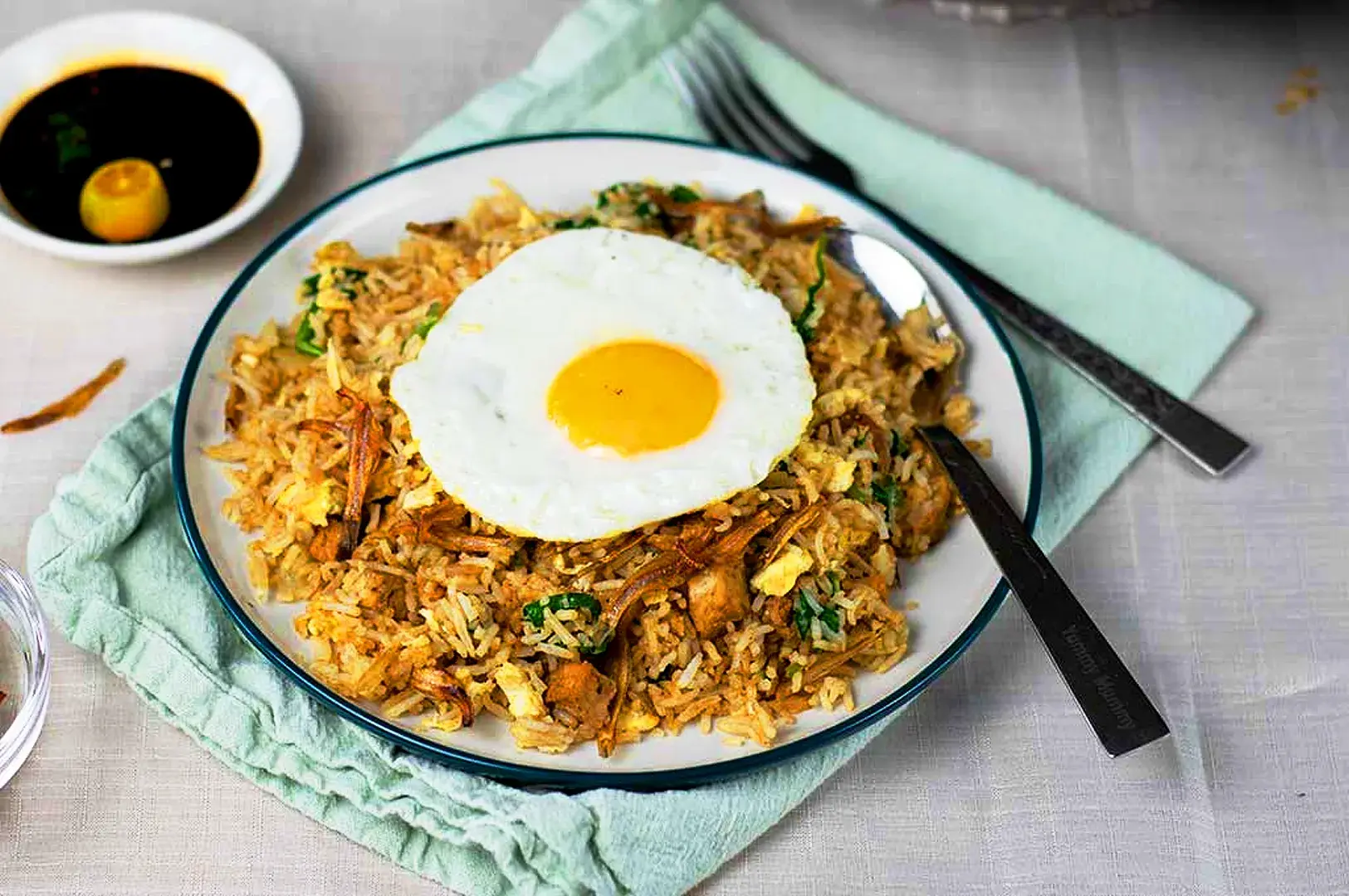 Homemade chicken nasi goreng topped with a fried egg and served with soy dipping sauce