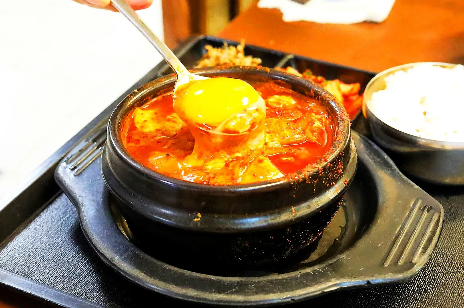 Korean sundubu jjigae soft tofu stew with egg served with rice and Korean side dishes