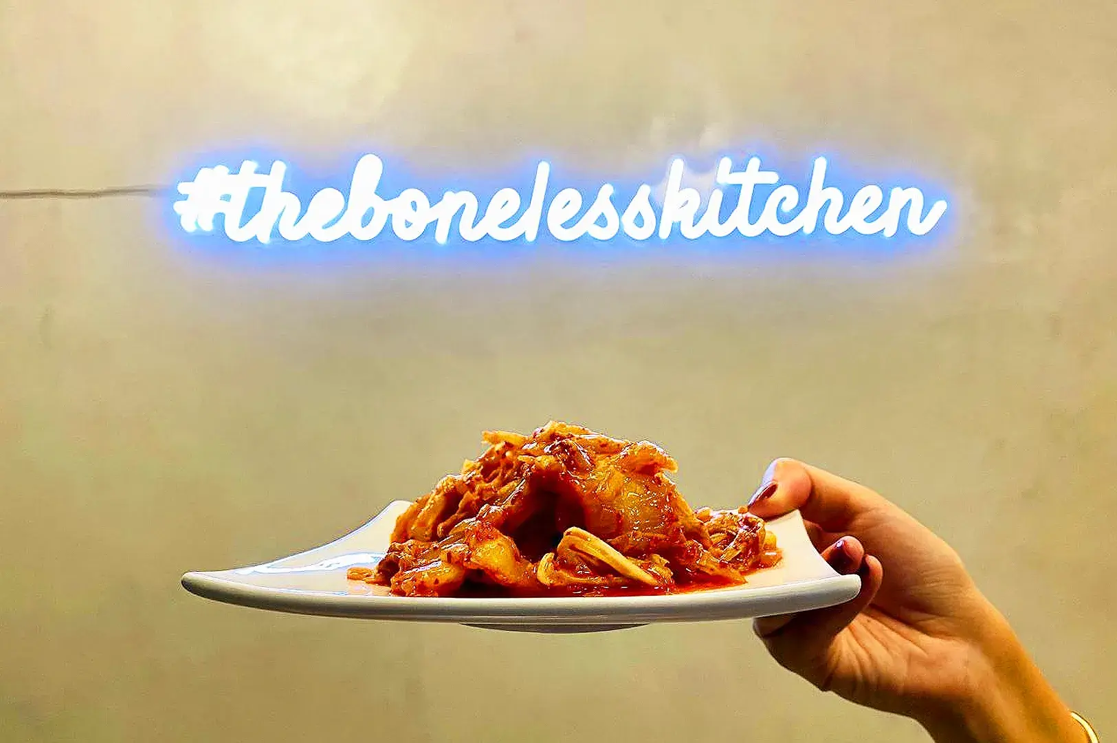 Korean kimchi dish served at The Boneless Kitchen Singapore with restaurant branding in the background.