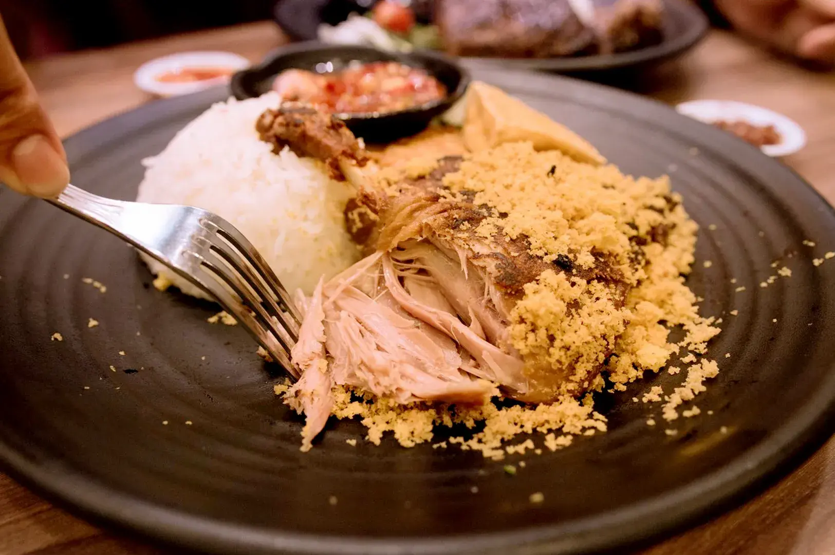 Bebek Goreng Pak Ndut fried duck served with rice, crispy savory topping, tofu, and chili sambal
