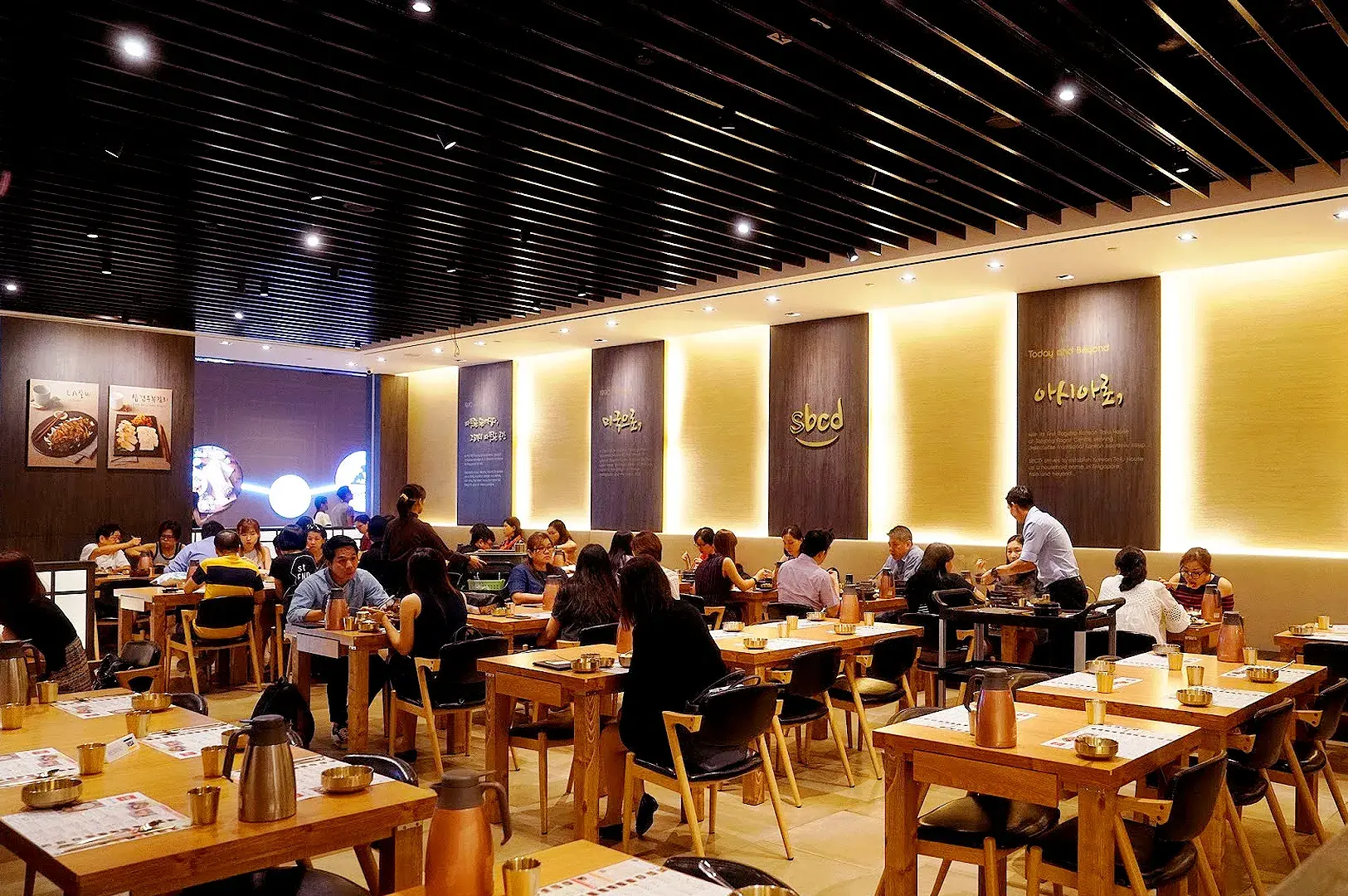 Busy SBCD Korean Tofu House dining area with wooden tables, Korean decor, and diners