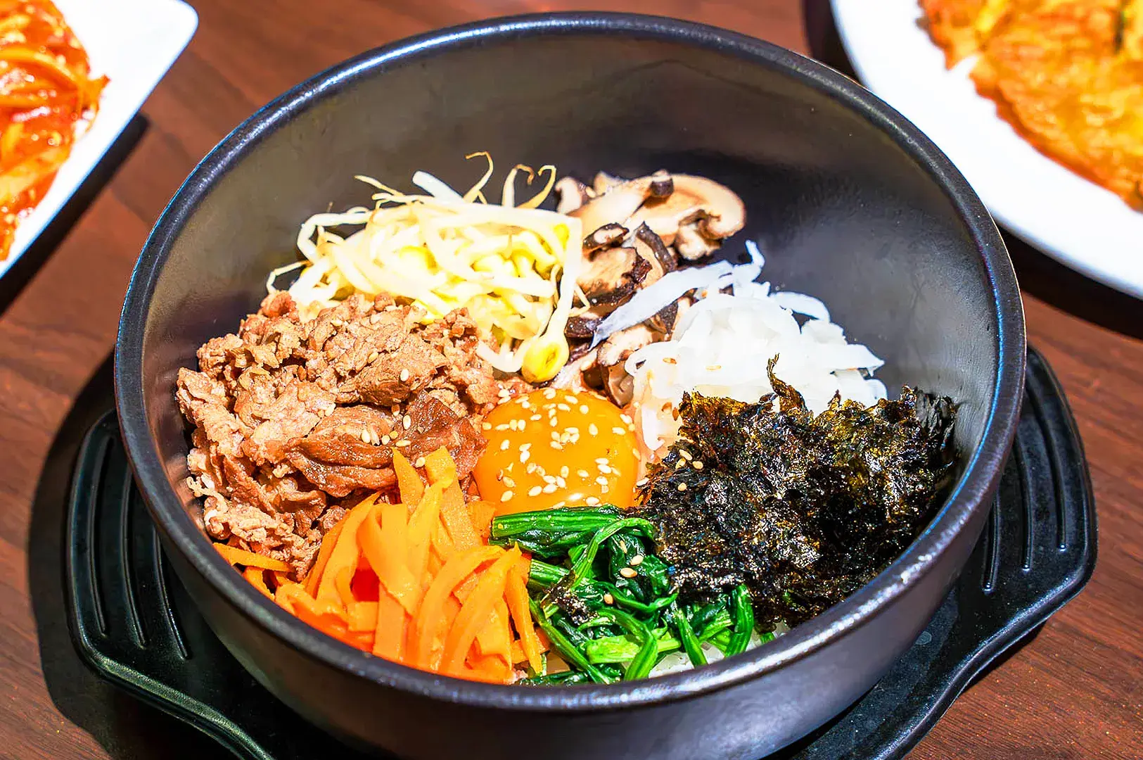 Korean bibimbap bowl with beef, fried egg, vegetables, mushrooms, spinach and seaweed