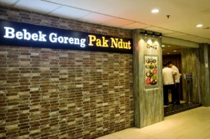 Bebek Goreng Pak Ndut restaurant entrance with illuminated sign and brick wall design