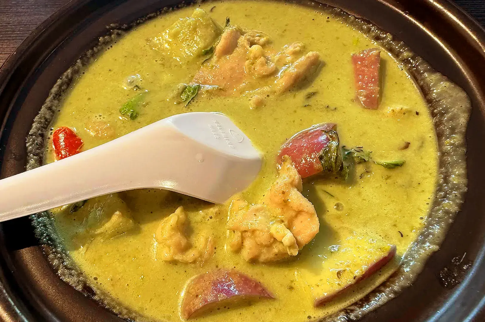 Thai green curry with shrimp, vegetables and aromatic herbs served in a traditional dish
