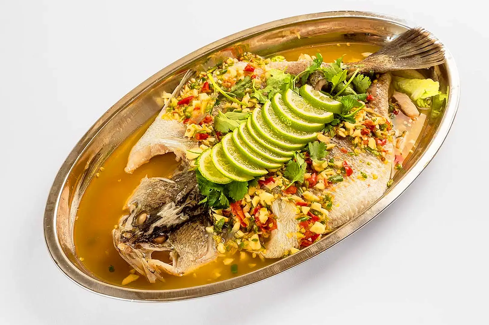 Whole steamed Thai-style fish with lime slices, fresh herbs, chili and garlic in savory sauce
