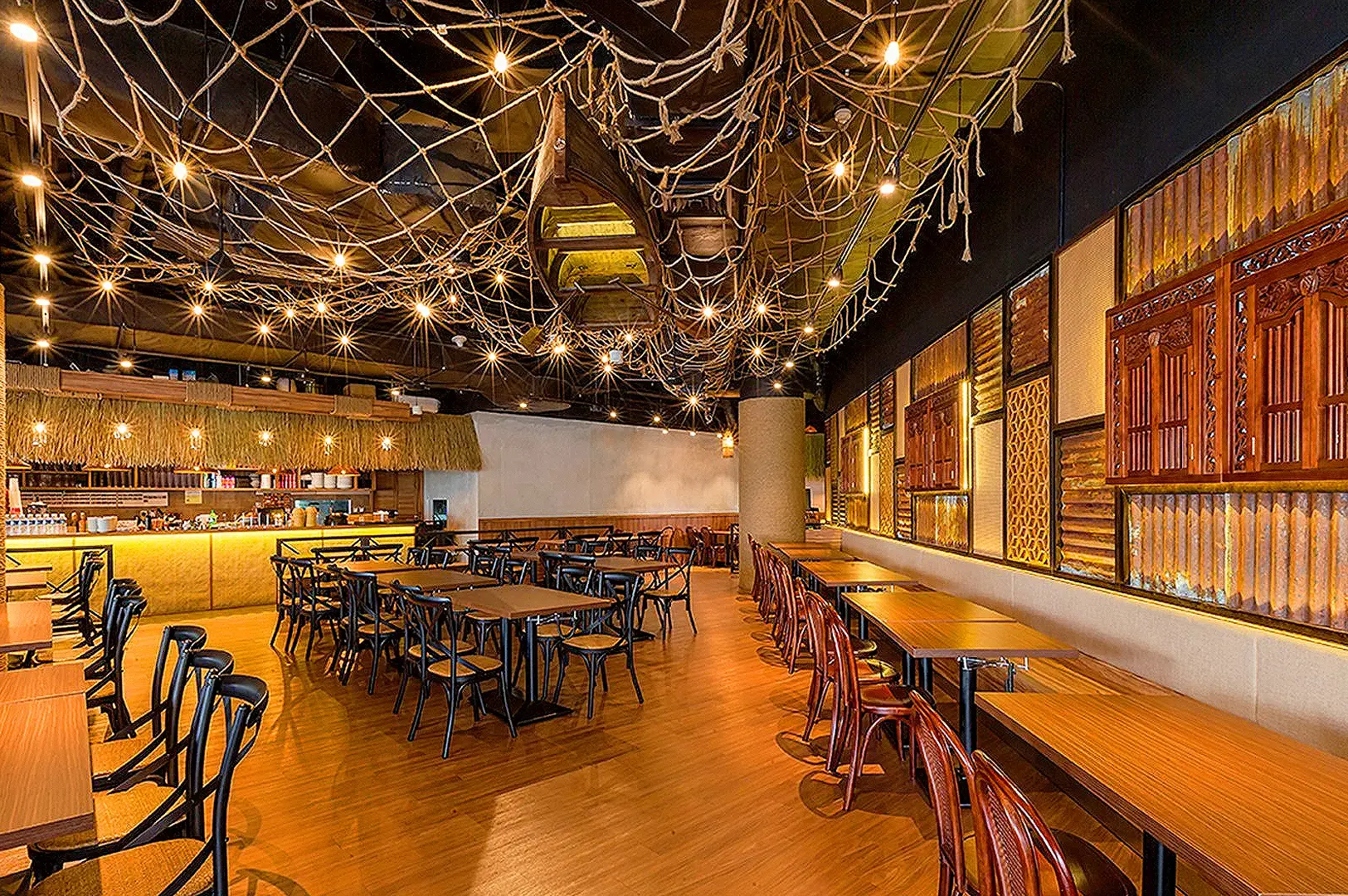 Yassin Kampung Seafood Admiralty restaurant interior with rustic tropical décor, wooden tables and warm ambient lighting