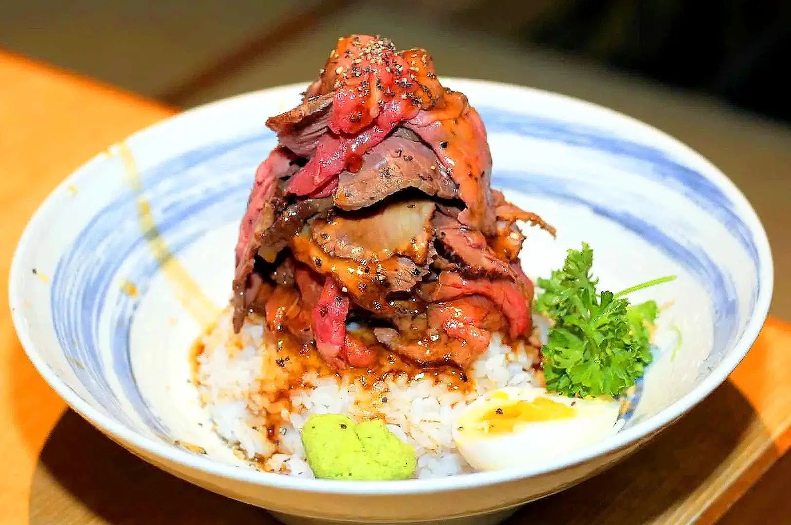 Sandaime Bunji Singapore beef tongue rice bowl topped with grilled beef, pickled vegetables, wasabi and egg
